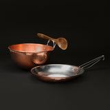 Copper omelette pan and mixing bowl, with a wooden spoon resting on the bowl’s handle
