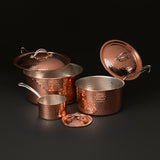 Three graduated saucepans with lids lifted to show their tin-lined interiors