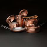 The stock pot, Dutch oven, and saucepan with lids lifted and a wooden spoon resting on the Dutch oven