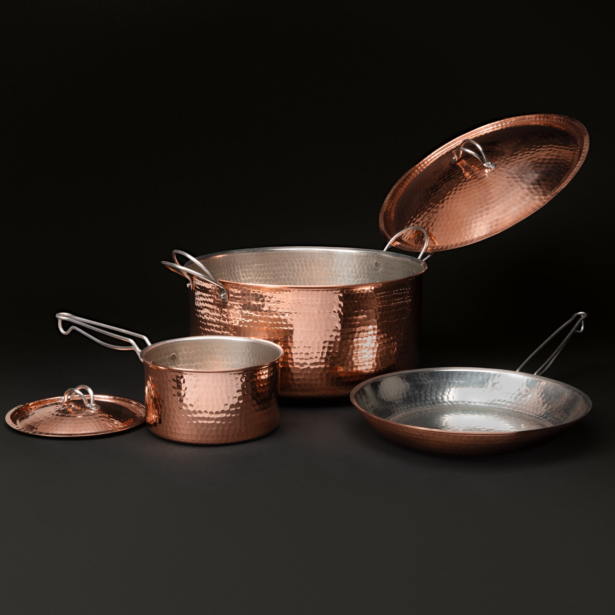 The Dutch oven lid propped open and the saucepan lid set beside the skillet
